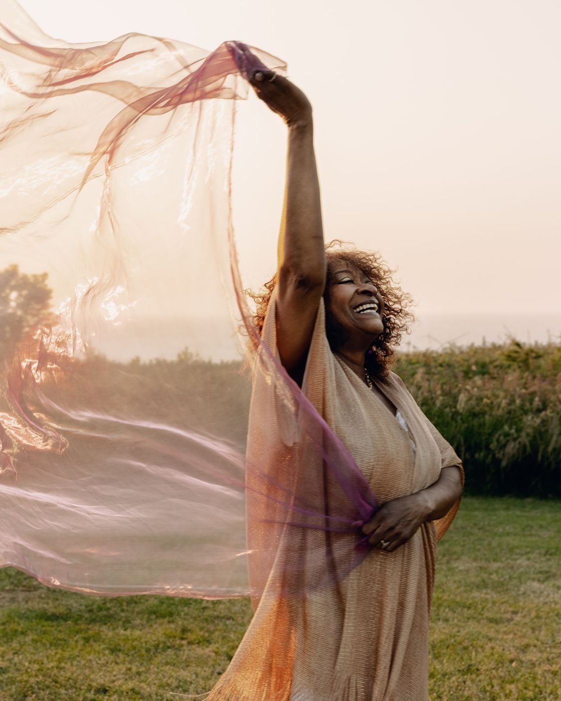 Linda Lee Hopkins bras levé, un voile rose et doré dans la lumière du soir
